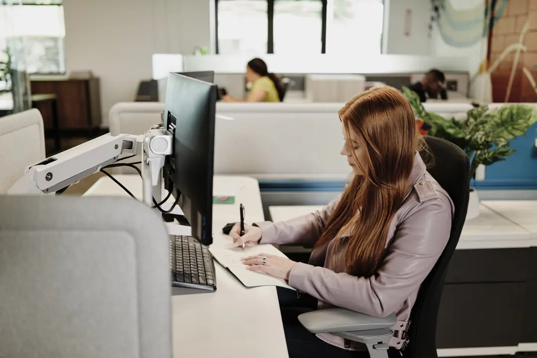 woman taking notes at her cubicle