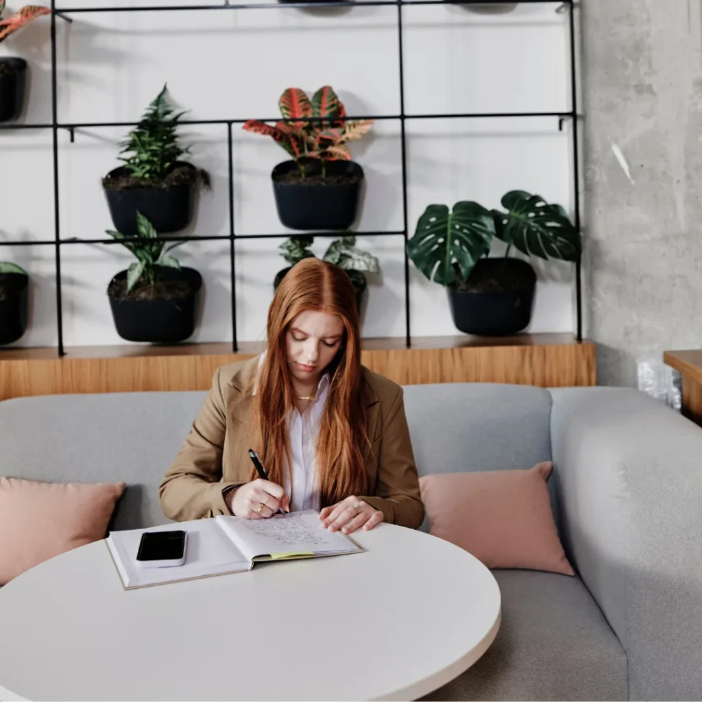 Young woman sits at a table and writes in a notebook in an office