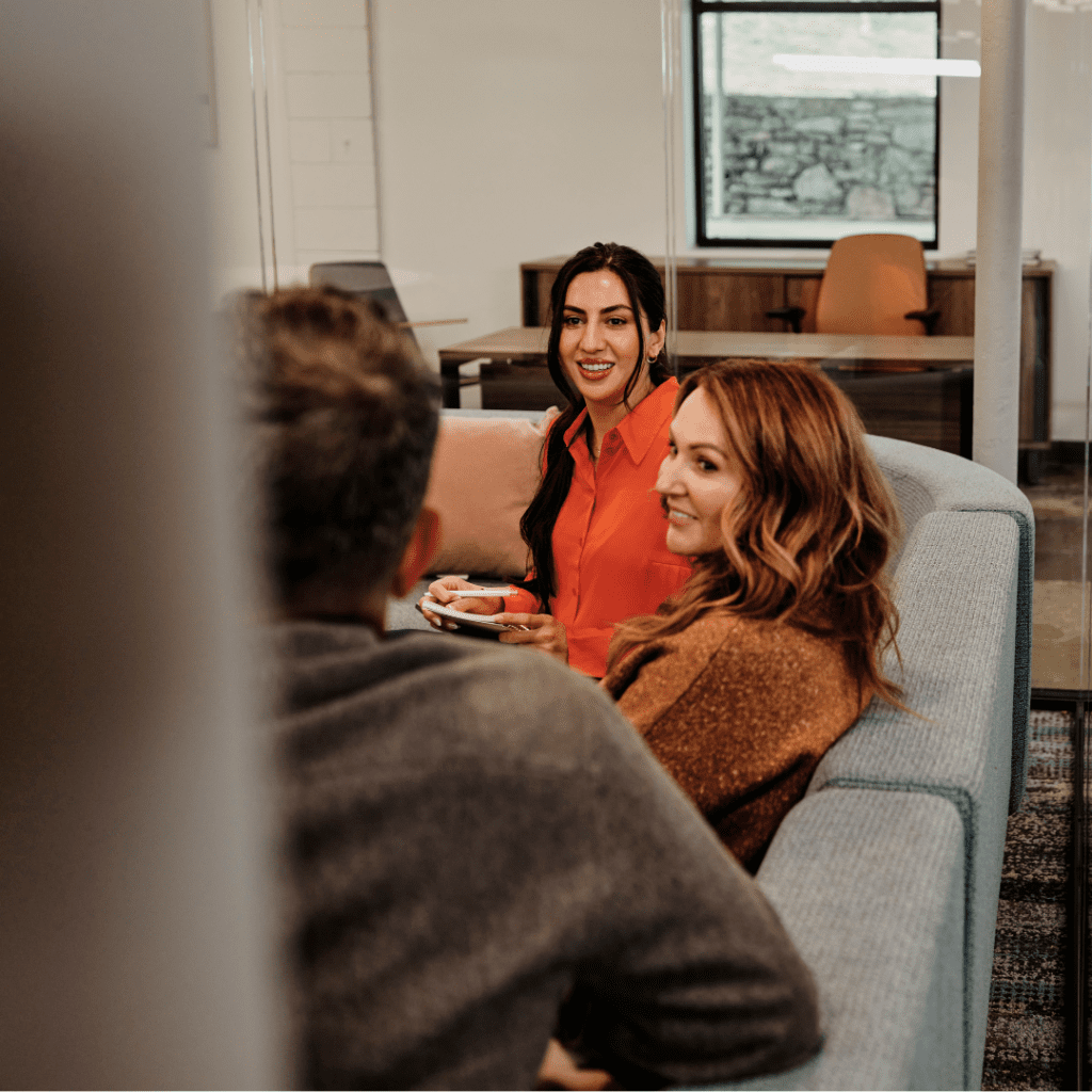 A group of coworkers have a conversation in a work sitting area.