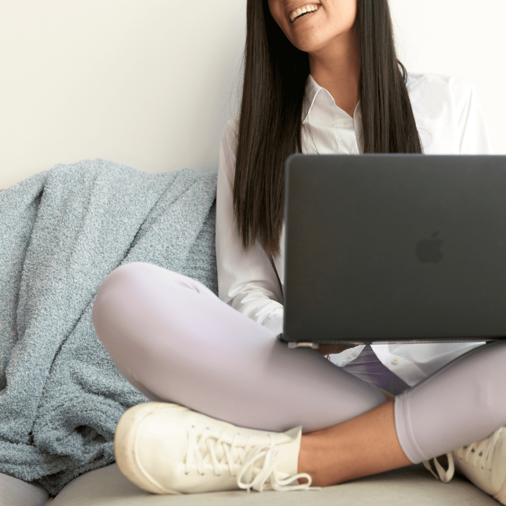 Smiling woman working on her laptop on her couch at home.