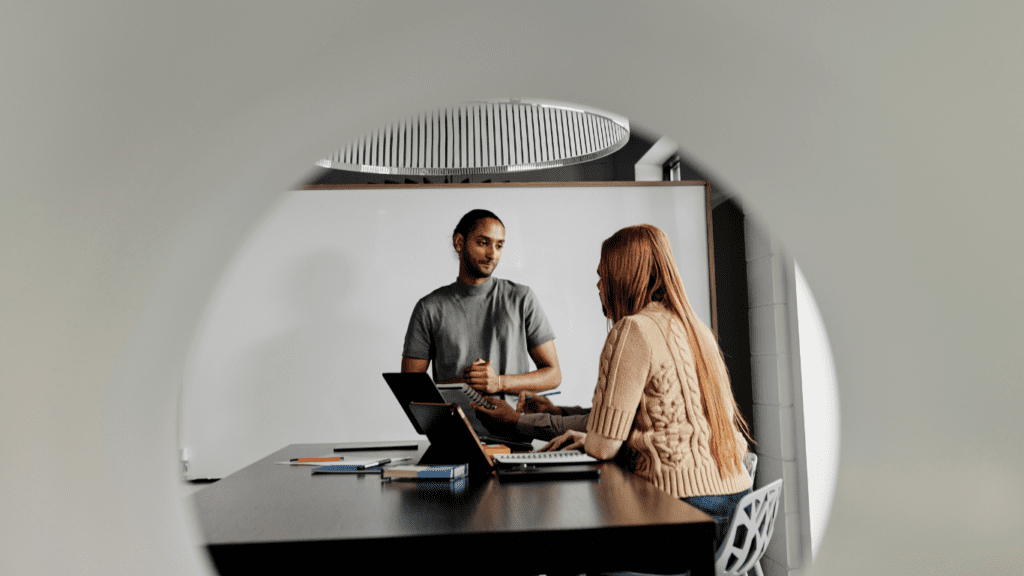 Two colleagues are chatting in a meeting in a conference room.