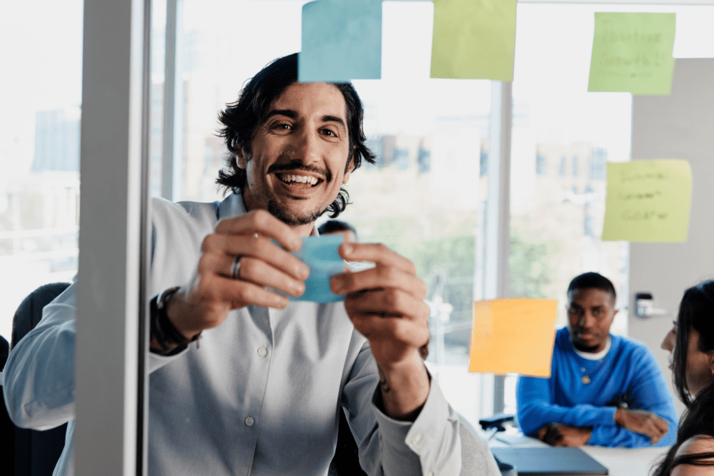 Excited employee puts on sticky notes on a conference room wall